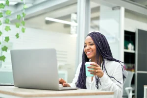 smiling-businesswoman-sitting-at-office-desk-holding-a-cup-of-coffee